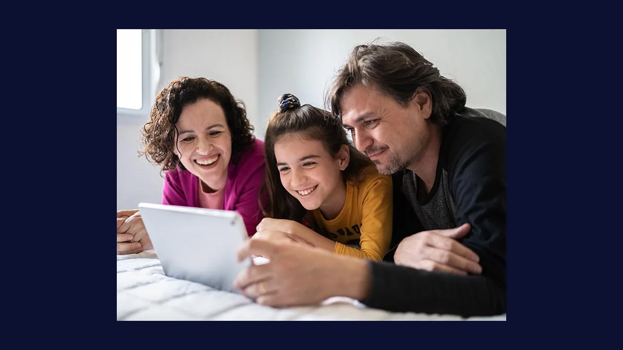 Photograph of a family playing a tablet game together on a sofa